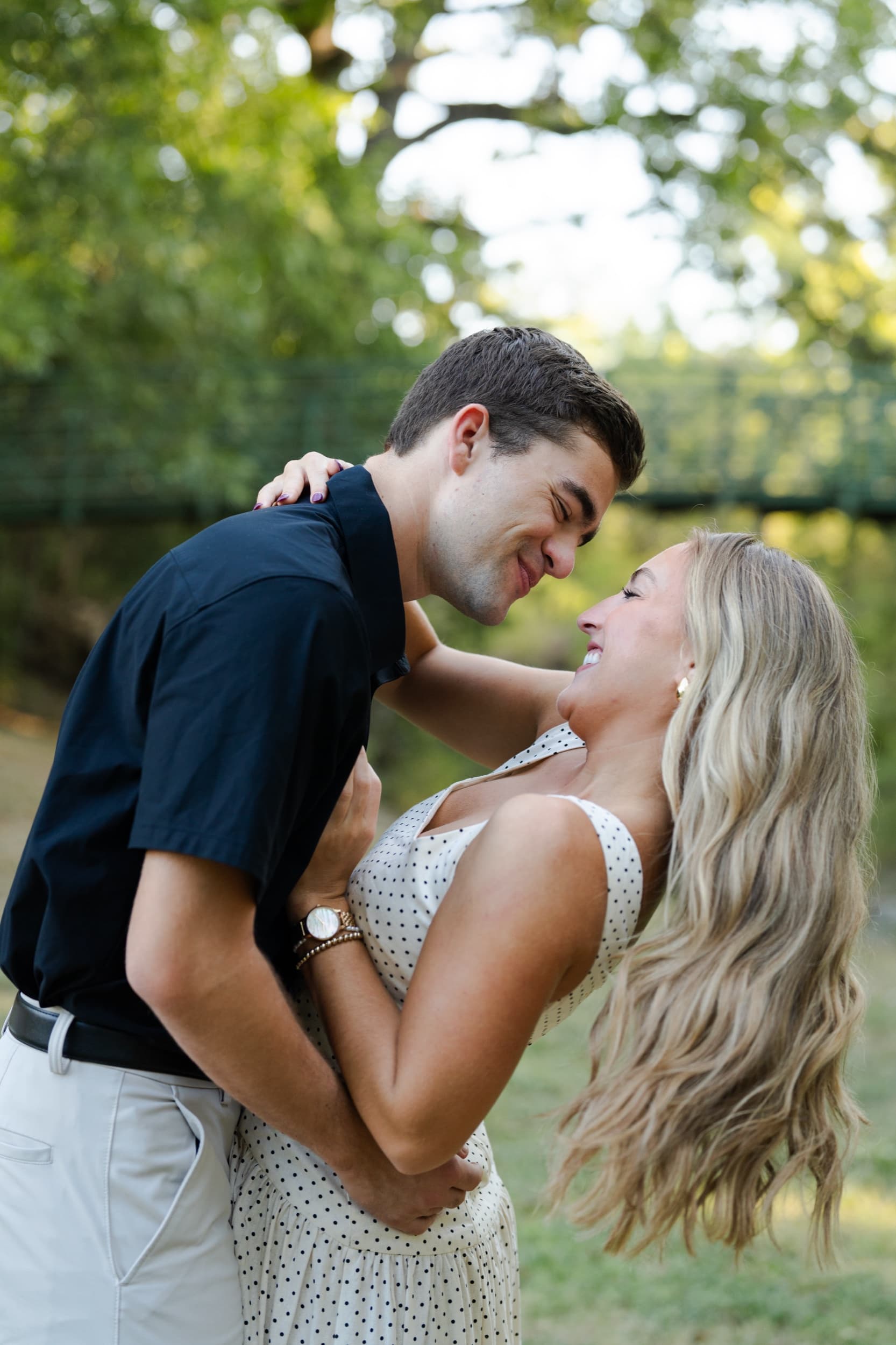 Man dipping down to nearly kiss his laughing partner, her arms wrapped around his neck.