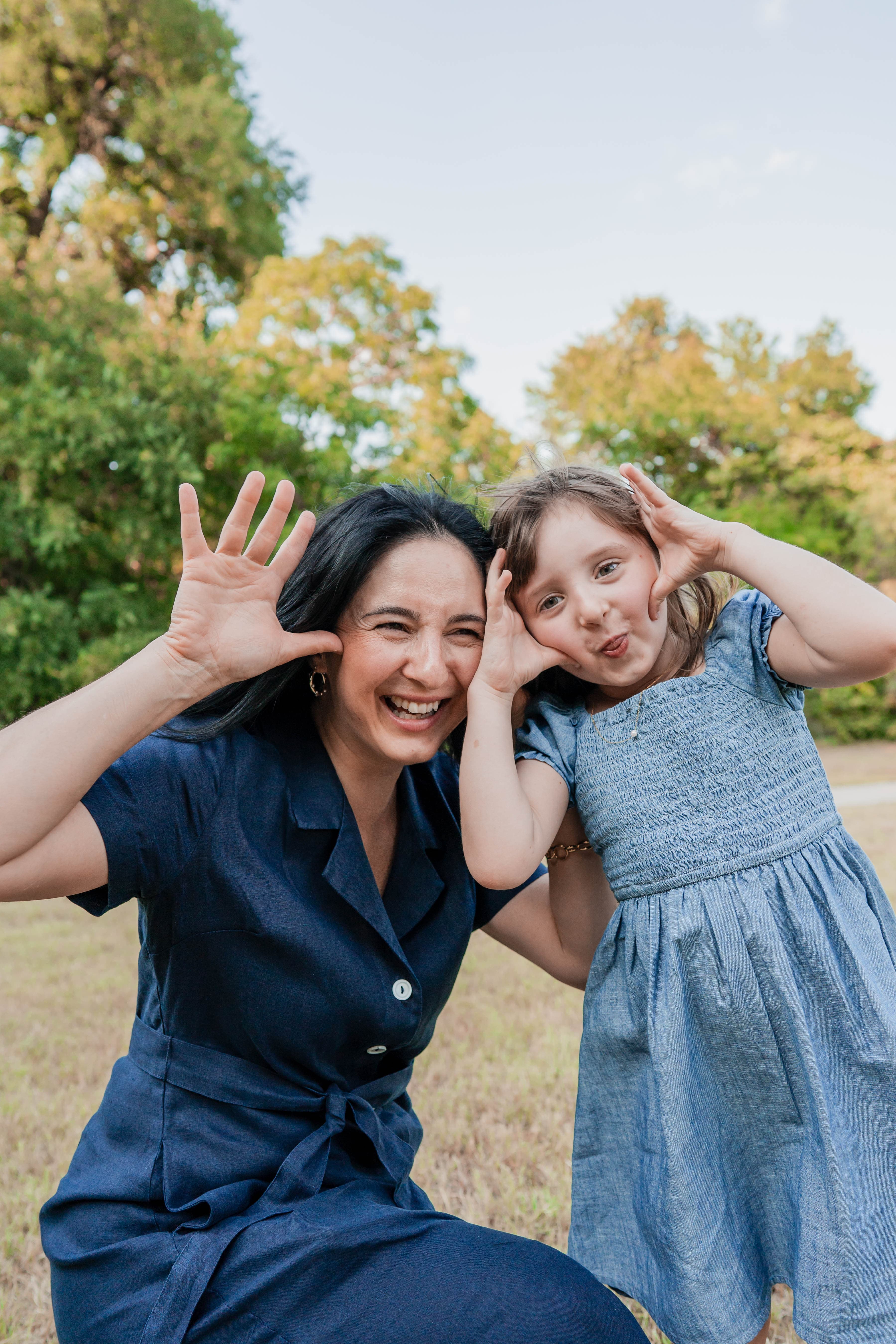 Mother and daughter making playful faces with their hands framing their cheeks.