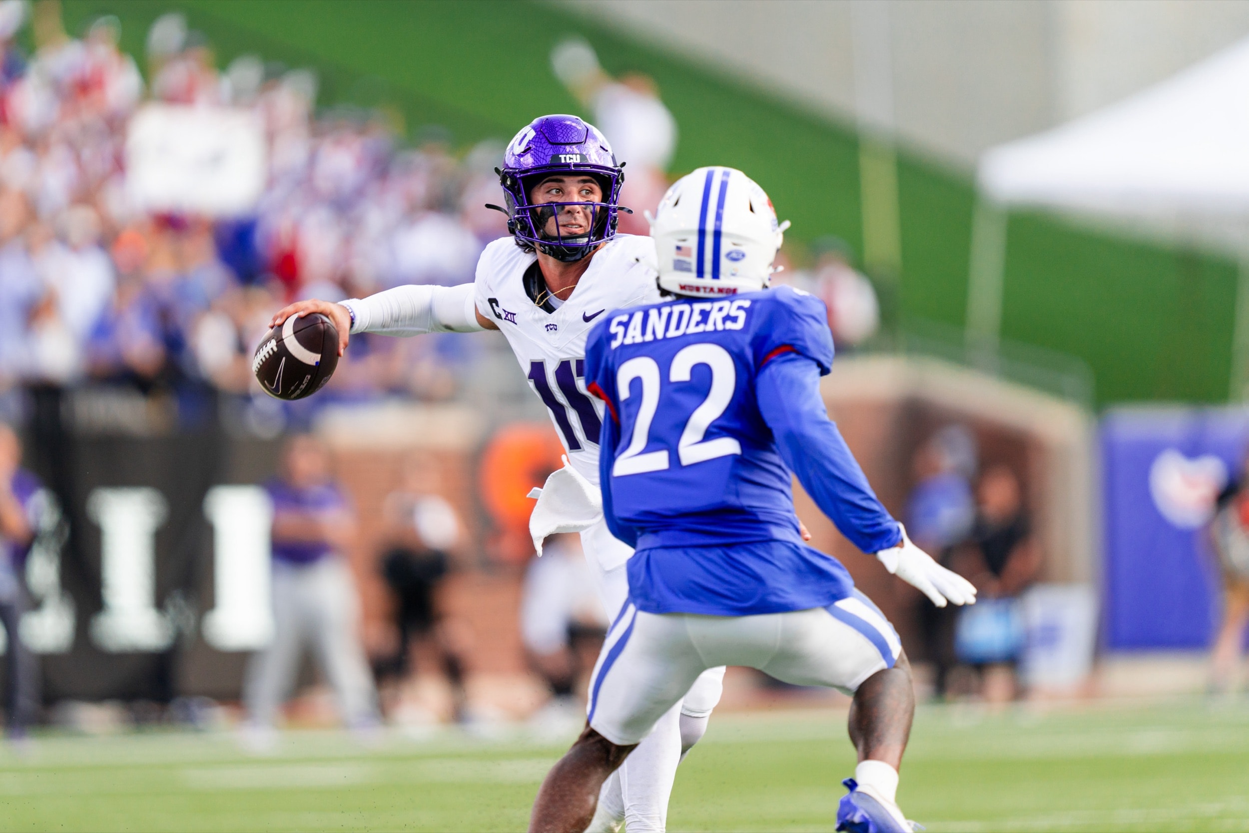 Quarterback winding up to throw as a defender closes in during a football game.