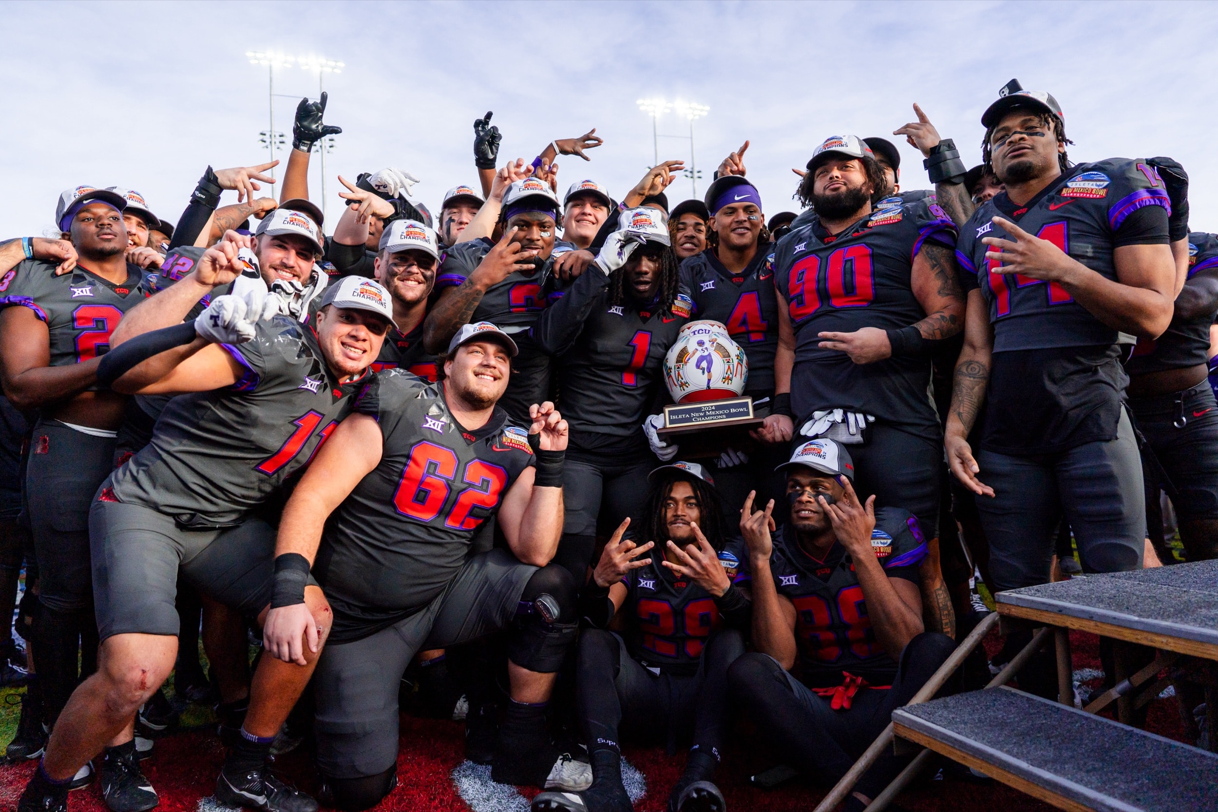Football team posing together with their championship trophy in a joyful group celebration.